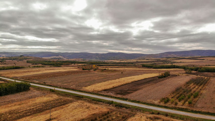 Fototapeta na wymiar Aerial view of countryside in autumn with yellow fields and clouds in the background