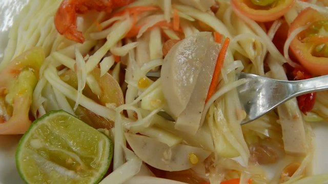Som tum Thai spicy green papaya topping slice Vietnamese sausage salad scooping by fork