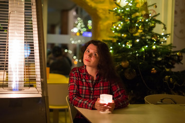 Holidays and people concept - Beautiful woman in cafe near Christmas tree background