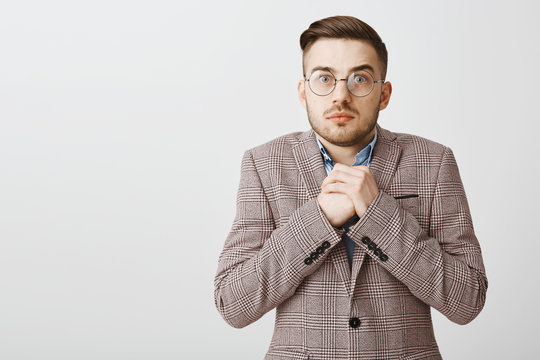 Waist-up shot of worried intense cute european man with bristle and cool haircut in formal jacket clenching hands near chest staring anxious and troubled at camera as if hearing shocking revelation