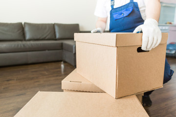Fototapeta premium Delivery man loading cardboard boxes for moving to an apartment. professional worker of transportation, male loaders in overalls
