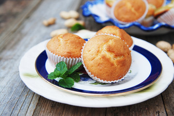Homemade vanilla muffins in white palte with blue streep. Rustic wooden background.
