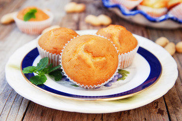 Homemade vanilla muffins in white palte with blue streep. Rustic wooden background.