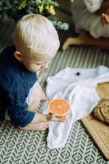 Little boy holding a half of grapefruit and looking at it