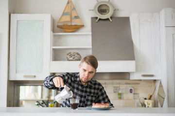 Young man smiling and holding a cup of coffee in kitchen