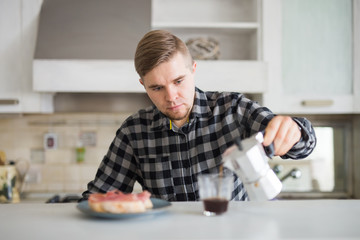 Young man smiling and holding a cup of coffee in kitchen