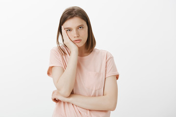 Fototapeta premium How long this lesson will last. Portrait of bored and sleepy cute woman in casual outfit, leaning head on palm and staring with indifference at camera, being annoyed and careless to what happening
