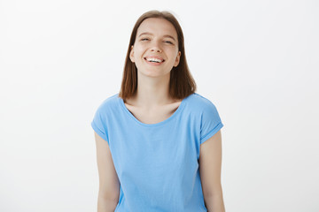 Fototapeta premium Waist-up shot of positive happy young female coworker in casual outfit, smiling broadly and gazing at camera with carefree and friendly attitude, talking with close friends and grinning, enjoying life