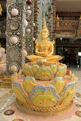 Golden sitting statue of Lord Buddha, sitting in a lotus, decorated with beautiful, colorful mosaic tiles at the entrance of at Pha Sorn Kaew, in Khao Kor, Phetchabun, Thailand.