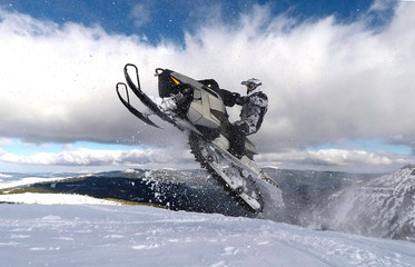 RIDER JUMPING WITH SNOWMOBILE BETWEEN CLOUDS