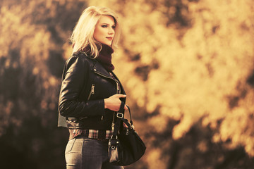 Fototapeta na wymiar Young fashion blond woman in leather jacket walking outdoor