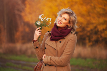 Happy young blond fashion woman wearing classic beige coat walking outdoor