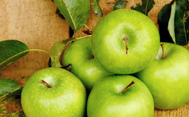 Green apples with leaf and water drop on wooden background.