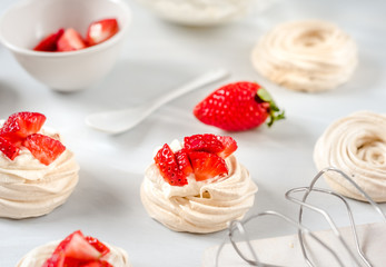 Strawberry pavlova cake nests, meringue decoration on a culinary table