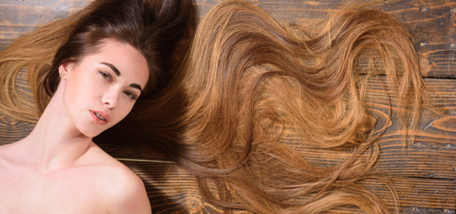 Long hair on wooden background with copy space. Beautiful model with curly hairstyle. Fashion haircut. Trendy haircuts.