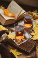 Tea in Turkish cups, books, yellow maple leaves at the window and a warm blanket - the concept of comfort and warmth in autumn.