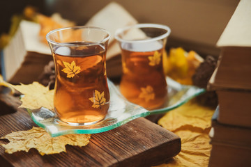 Tea in Turkish cups, books, yellow maple leaves at the window and a warm blanket - the concept of comfort and warmth in autumn.