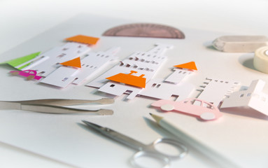 Fototapeta premium Paper cut design elements with tools: scissors, knife, pare, glue etc. Creation a city view in progress. Creativity, education, hobby, innovation and inspiration concept.