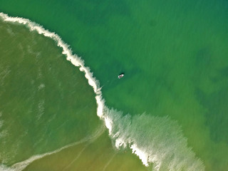 Aerial view at beautiful sea with small fishing boat in the center.