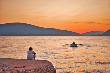 Naklejka na ściany i meble man in a boat with oars at sunset