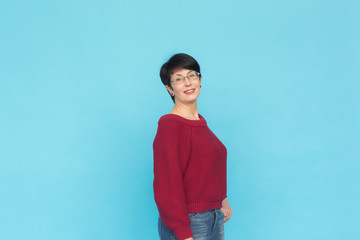 Fashion, people and style concept - Mid-aged woman in crimson sweater on blue background with copy space