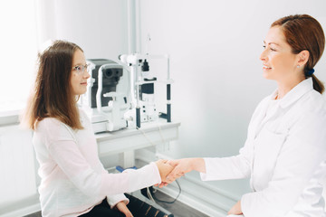 Fototapeta premium Handshake with patient, teenage girl's patient at optometrist office. Doctor, consultation and reception of children
