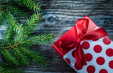 Wrapped gift box fir branches on wooden board