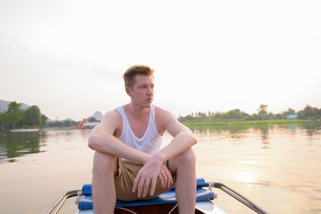 Fototapeta na wymiar Tourist man sitting in boat while having holiday in Thailand