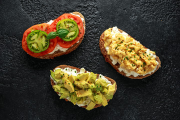 Vegetarian Healthy bread toasts with cottage cheese, heirloom tomatoes, scrambled eggs and avocado
