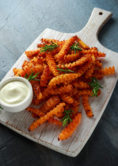 Baked butternut squash fries with sea salt and rosemary. Pumpkin chips on white wooden board.