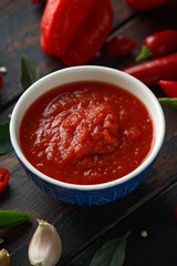 spicy hot sweet chili sauce with mix of chilli pepper, garlic and tomatoes on rustic wooden background