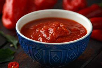 spicy hot sweet chili sauce with mix of chilli pepper, garlic and tomatoes on rustic wooden background