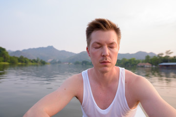 Naklejka na ściany i meble Tourist man sitting in boat while having holiday in Thailand