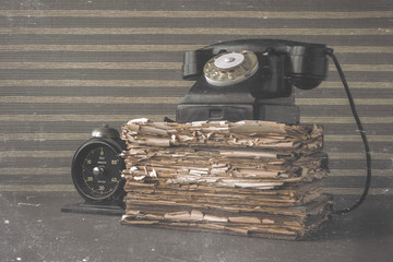 Old black phone and stack of battered books