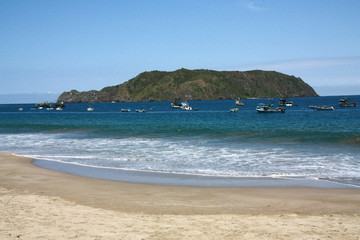 Obraz premium Many fisherman boats still on the sea, between the beach and an island. Ecuador.