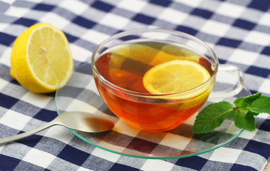 Lemon tea in transparent cup on checkered cloth
