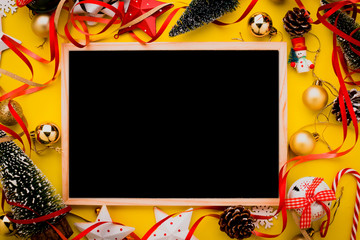 festive celebration background with christmas decorating items on yellow paper background with free copy space for your text
