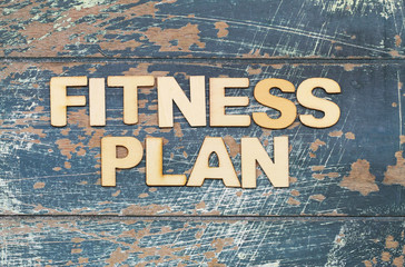 Fitness plan written with wooden letters on rustic wooden surface
