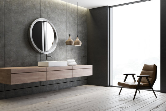 Sink and mirror in concrete bathroom, armchair