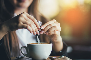 Fototapeta Female hand pours sugar into coffee. Sunlight background obraz