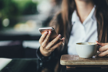 Portrait of beautiful girl using her mobile phone in cafe. Close up