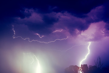 A lightning strike on the cloudy sky. Pink, lilac and purple toned image lightning, storm, danger,