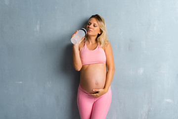 Blonde pregnant woman doing sport with a bottle of water