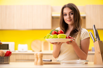 Young woman preparing salad at home in kitchen