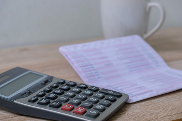 calculator, bankbook ,coffee cup  Put on a wooden table.