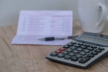 calculator,pen , bankbook ,coffee cup  Put on a wooden table.