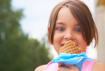 Closeup of ice cream held in hand by cute young girl. Little Caucasian girl eating ice cream in a waffle cone.