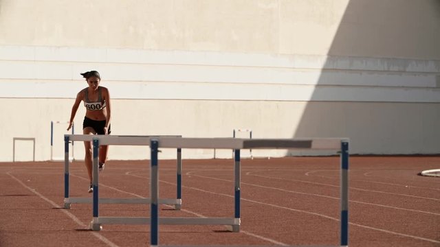 Female athlete on track. Young asian runner running on track of stadium, jumping over barriers, preparing for competition