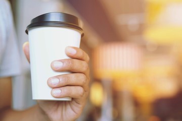 young man hand holding Paper cup of take away drinking coffee hot on cafe coffee shop.	