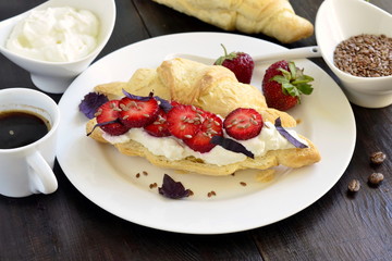 Croissant with cream cheese, strawberries and basil for breakfast